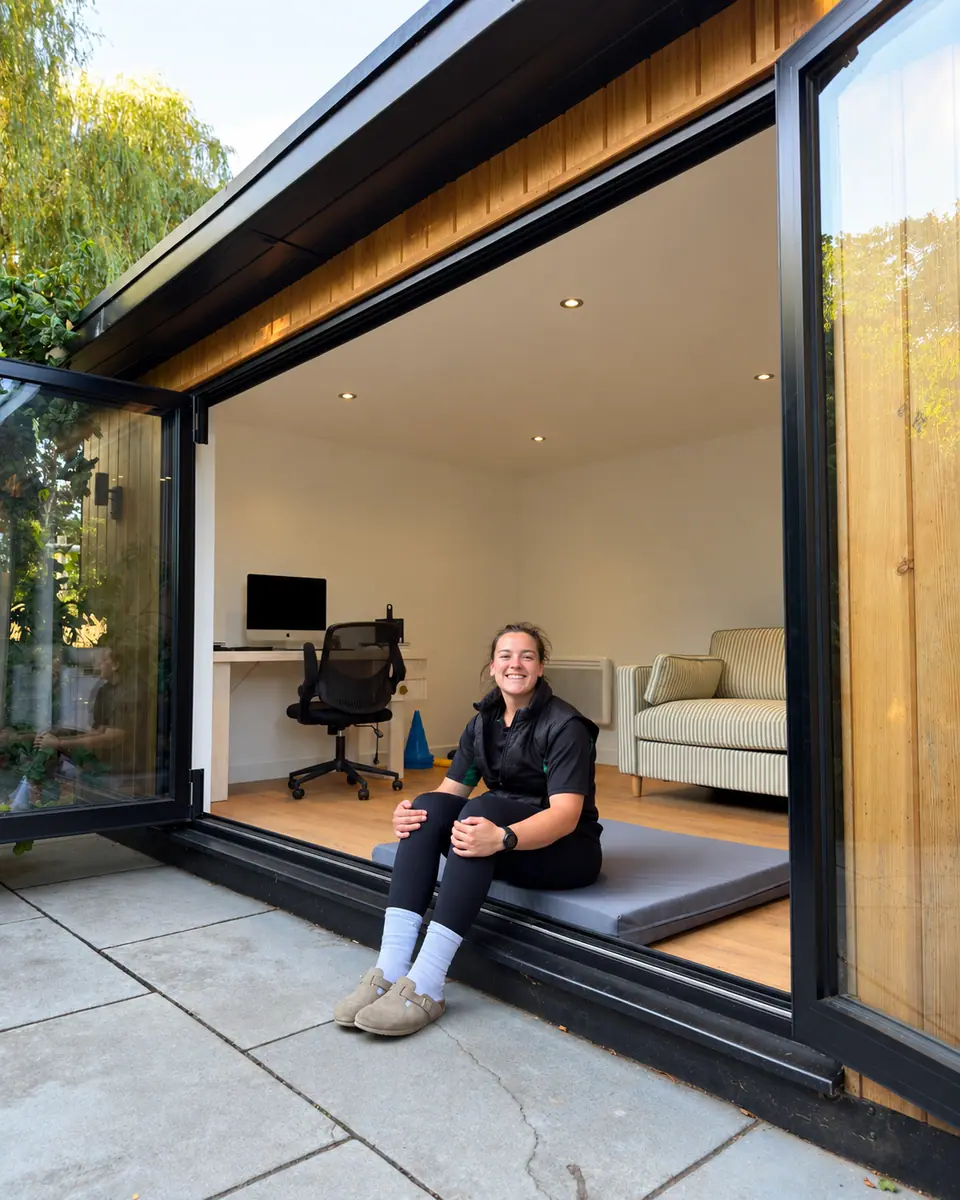 Kate Darlison smiling in the doorway of her garden-room clinic