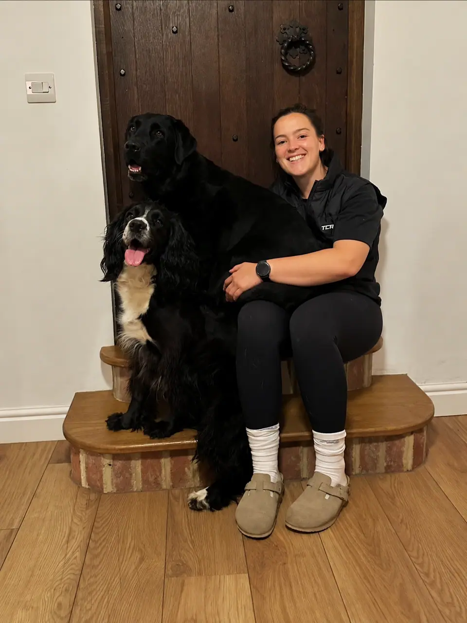 Kate sitting on a doorstep with her black Labrador and her spaniel